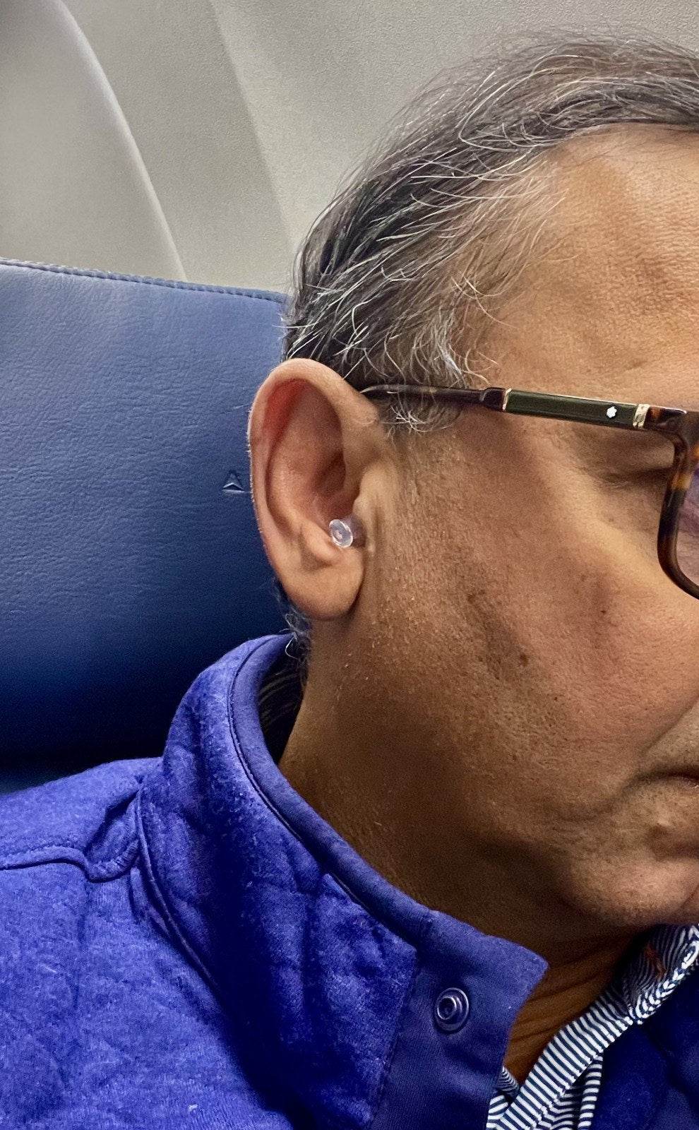 Traveler wearing an Auricula Air earplug on a flight