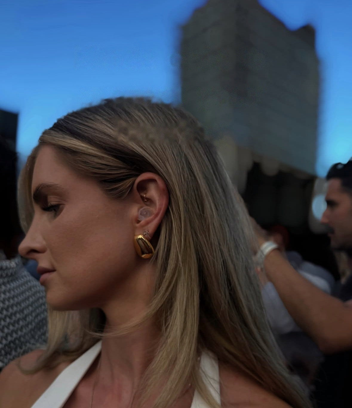 Woman at a rooftop party wearing a clear Auricula earplug